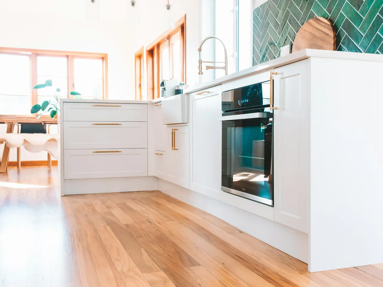 New Zealand home kitchen with white cabinetry, timber flooring and green splashback tiles